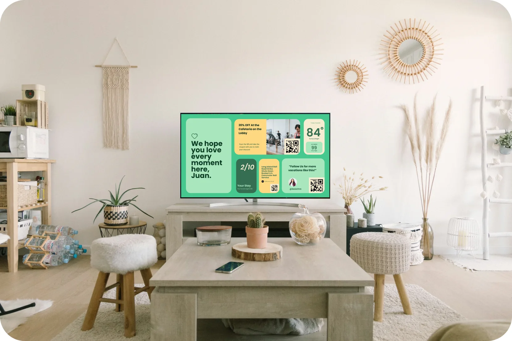 A living room where the TV shows a Stayboard welcome screen greeting a guest by name, with weather, Wi-Fi and local offers.